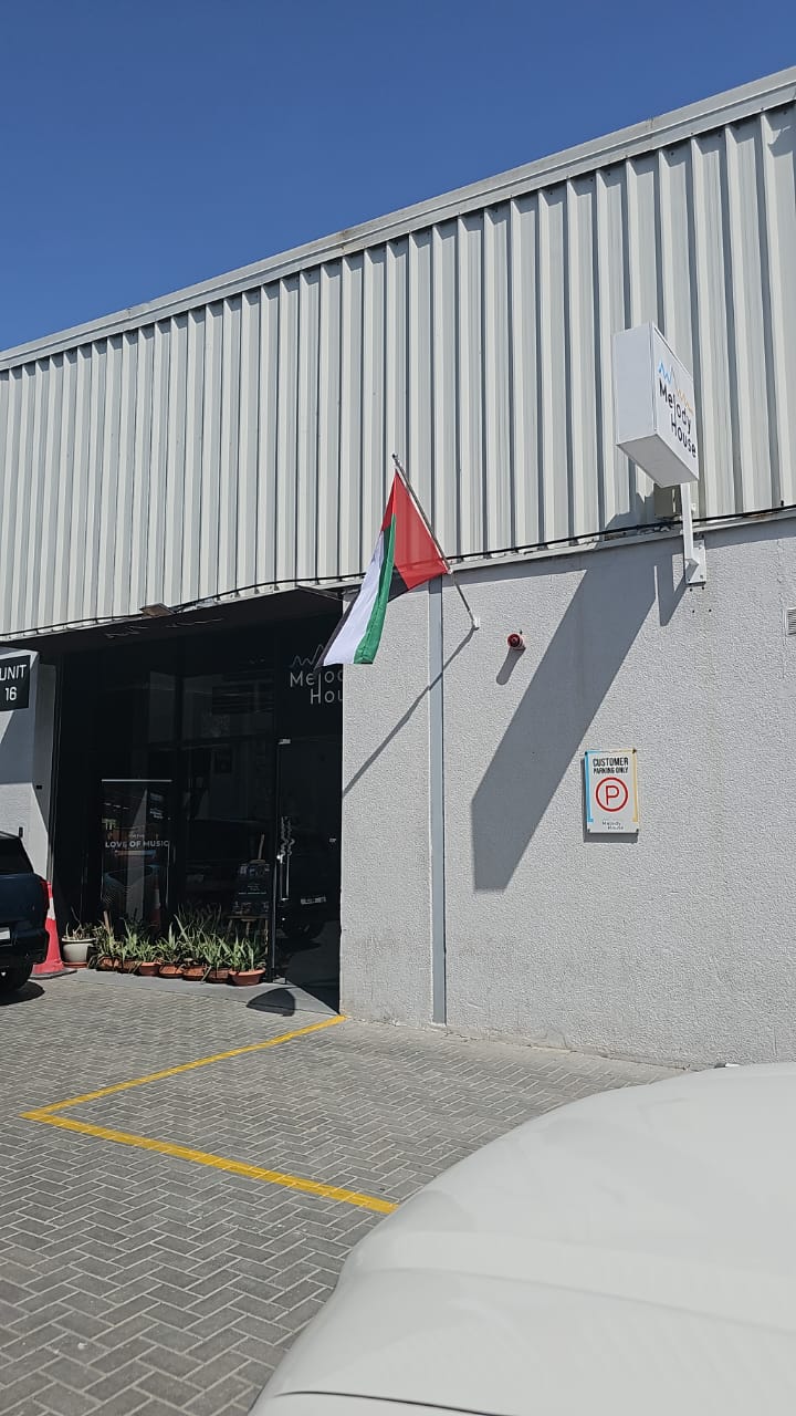 Wall flag pole with bracket and UAE flag at shopfront