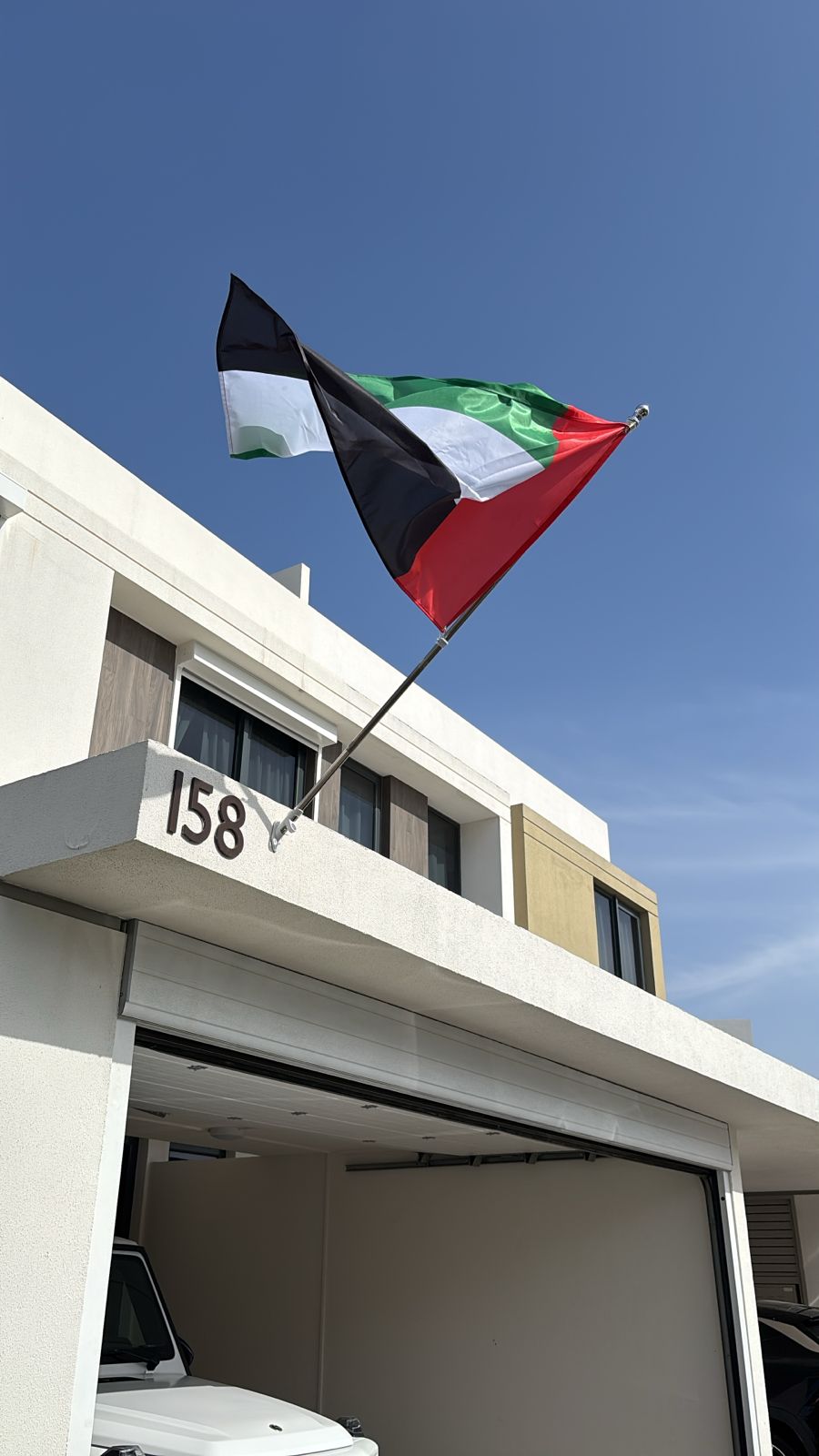 Wall-mounted flag pole with UAE flag above villa garage